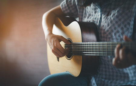woman playing acoustic guitar sitting in public park in a relaxed. Woman practicing playing guitar...