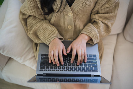 Top view. Asian freelance woman smile lying relax and typing on keyboard and working on laptop on...