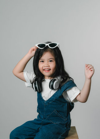Portrait of relaxed cute little asian girl child funny smiling and laughing wearing white headphones...