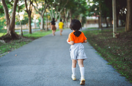 Happy baby asian girl smiling. little girl running and smiling at sunset happy baby girl smiling. little baby running at sunset. cute baby running at playground garden.の写真素材