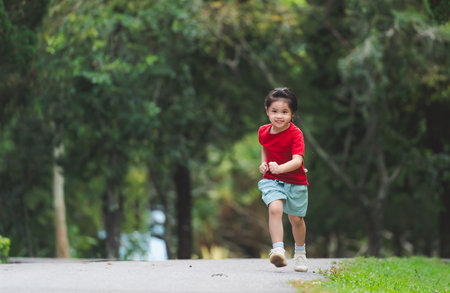 Happy baby asian girl smiling. little girl running and smiling at sunset happy baby girl smiling. little baby running at sunset. cute baby running at playground garden.の写真素材