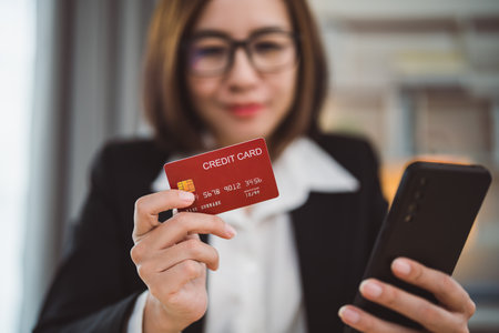 Businesswoman holding credit card and using laptop computer to shopping online. Businesswoman working at home. Online shopping, e-commerce, internet banking, spending money, shopping from anywhere.の写真素材