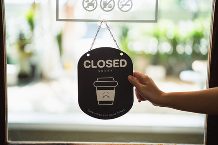 Hand woman hold open sign broad through the door glass. CLOSE sign board through the glass of store window. text wooden board door vintage shop sign opened store.の写真素材