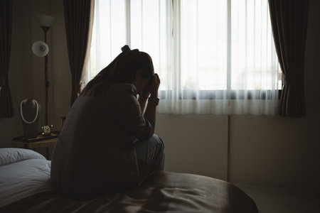 Silhouette depressed woman sadly sitting on the bed in the bedroom. Sad asian women suffering depression insomnia awake and sit alone on the bed in bedroom. Depression health people concept.の写真素材