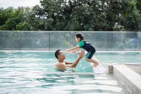 Father and daughter kid girl child swimming playing in the pool, smiling and laughing. Having fun in...