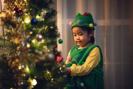 Children kids girl hanging a small glitter ball decorating christmas tree for celebrate christmas and new year party at home. Preparing for holiday. Happiness Christmas day. Have fun. X-mas concept.の写真素材