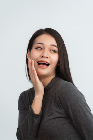 Asian woman braces. Teeth braces on the white teeth of women to equalize the teeth. Bracket system in smiling mouth, close up photo teeth, macro shot, dentist health concept.の写真素材
