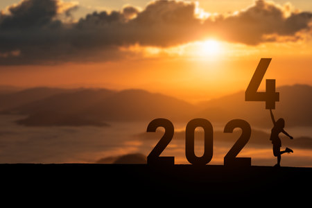 Woman holding standing happy new year 2024 concept, silhouette of woman stand lawn and success with beautiful sunset background. Happy New Year 2023 use for web banner and advertisement.の写真素材