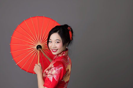 Portrait photography. Asian Chinese woman smiling in traditional cheongsam qipao dress on White or grey background. Chinese new year festival concept.の素材
