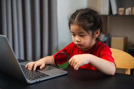 Asian baby kid girl holding magnifying glass and using laptop education to get good ideas, children...