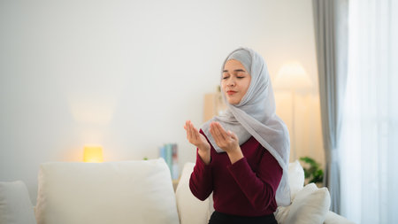 Muslim Islam woman with hijab do a day pray that show her believe in god. Muslim women praying in the living room at home.の写真素材