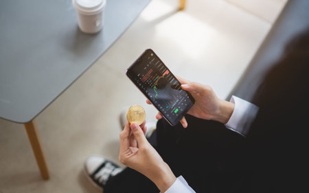 Businesswoman is holding a phone and a bitcoin cryptocurrency sitting on the couch sofa, possibly a...