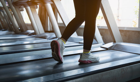 Close up of feet, sportman runner running on treadmill in fitness club. Cardio workout. Healthy...