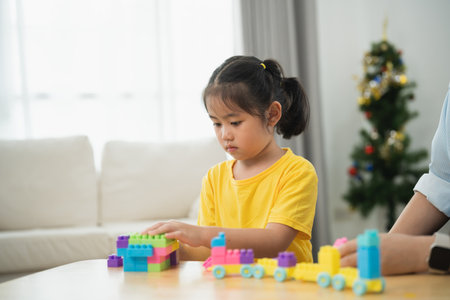 Asian woman and a child are playing with blocks. The woman is helping the child build a towerの写真素材