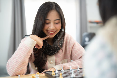 Young Woman Enjoys Intense Chess Game with Focused Expression while Strategizing Around the Game Board in Bright Living Room Settingの写真素材