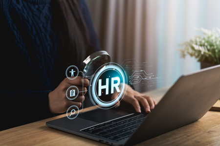 Close-up hand woman analyzes HR data using a laptop and magnifying glass in a modern office, showcasing the integration of technology in human resources management and employee evaluation.の写真素材