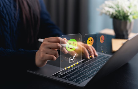 Close-up hand woman interacts with a laptop to express feedback using emotion icons and star ratings, reflecting the importance of customer satisfaction digital workplace.の写真素材