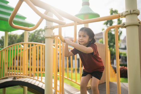 Young girl climbing playground equipment under bright sunlight enjoying outdoor activity in a...