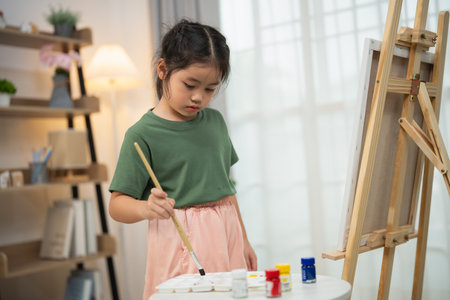 Creative young girl focused on painting in art studio, exploring her artistic talents and enjoying colorful activities with brushes and paintsの写真素材