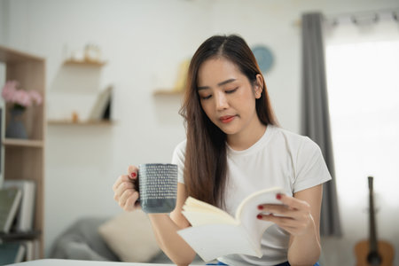Young woman enjoying a cozy moment reading book while sipping coffee in a comfortable living room,...