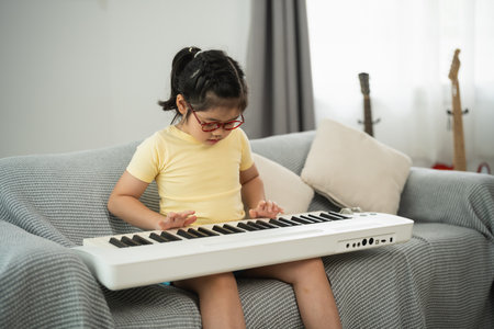 Young Girl Playing Keyboard in Cozy Living Room Setting, Music Education, Home Activity, Creative Learning, Joy of Music and Development of Skillsの写真素材