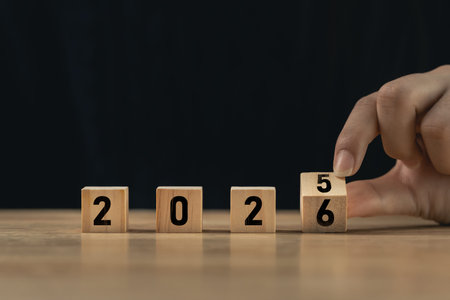 Creative concept of changing the year from 2025 to 2026 using wooden blocks with numbers,...
