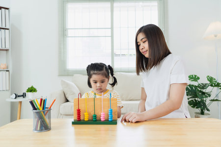 Child Learning with Abacus in Bright Room, Engaging Activities for Cognitive Development, Educator Assisting Young Learner at Homeの写真素材