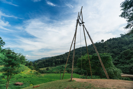 Tranquil Landscape Featuring Traditional Wooden Structure Against Scenic Mountains and Lush Green Fields Under a Blue Sky with Cloudsの写真素材