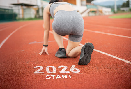 Athletic Female Runner Preparing to Start Race on Track Marked 2026, Signifying Future Competitions and Goals in Sports and Fitnessの写真素材