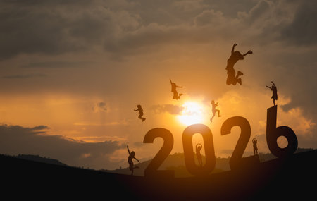 Excited People Jumping with Joy to Welcome the Year 2026 Against a Beautiful Orange Sunset Sky in a...