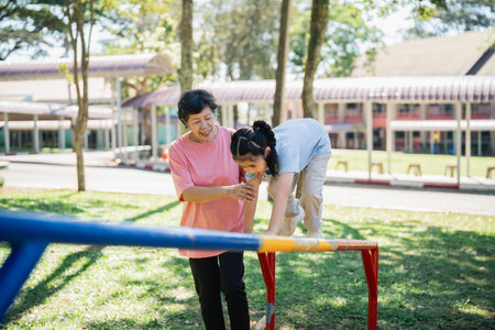 Joyful Interaction between Grandmother and Granddaughter at Playground with Bright Sunshine and Lush Greenery Creating a Warm Family Momentの写真素材