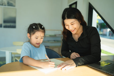 Caring mother assists daughter with art project at home, showcasing creativity and bonding moments...