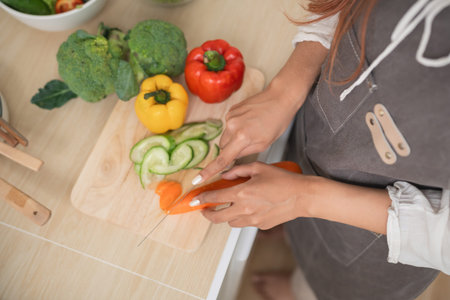 Fresh vegetable preparation in a cozy kitchen, focused hands slicing colorful ingredients on a...