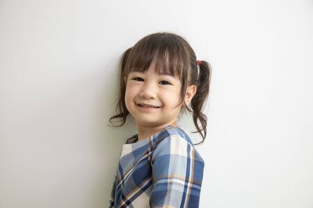 half-body and front-view photo of adorable, three-year-old Asian girl posing on a white background shows her brightness that makes people look happy, bright and cute.の写真素材