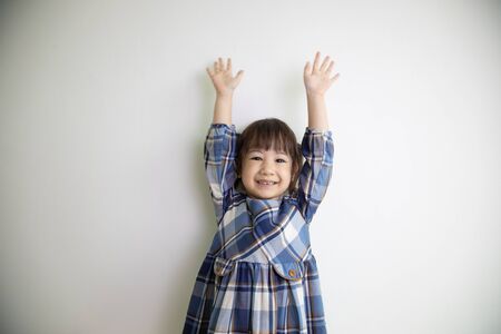 half-body and front-view photo of adorable, three-year-old Asian girl posing on a white background shows her brightness that makes people look happy, bright and cute.の写真素材