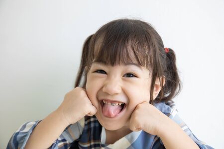 half-body and selective focus photo of adorable, three-year-old Asian girl posing on a white background shows her brightness that makes people look happy, bright and cute.の写真素材