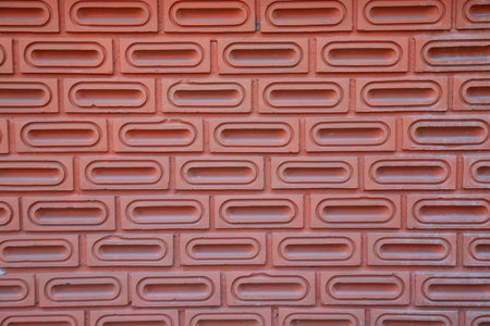 The red brick wall is orange, as background, which is made from the bricks that are ellipsoid...