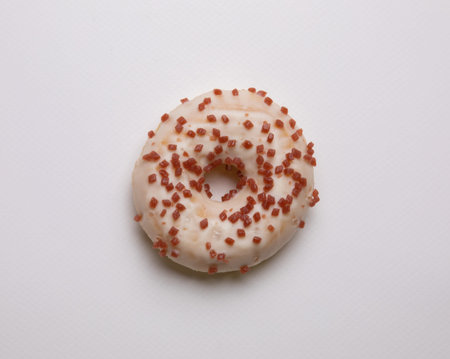Donuts topped with icing sugar and sprinkled with sugar, pink flakes placed on a white background...