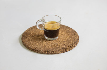 Newly brewed espresso coffee smelling fragrant and frothy places on a corck mat for a fresh,...