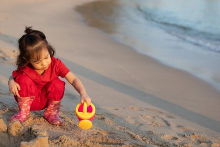A cute asian girl is playing happily on the beach in the evening sunの写真素材