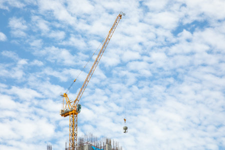 Yellow metal crane is working to construct the building for urban growing business. It seems the...