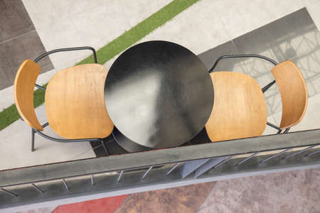 Top view of black round table with two wooden chairs with nobody in modern style department store for meeting, dining and relaxing shows concept of social distance and space for business discussion.の写真素材