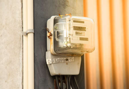 Close up shot of electricity meter attached on the electrical concrete pole in Thailand shows measuring the usage electricity, which the bill will be sent to the resident, of the house in the city.の写真素材