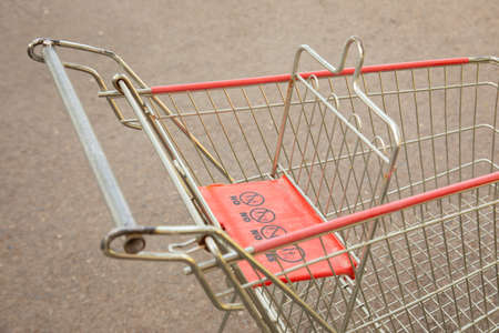 Close up and selective focus shot of empty shopping cart or trolley abandoned outside the shopping mall on the road shows detail of signs, and people habit to left it after delivering all stuffs.の写真素材
