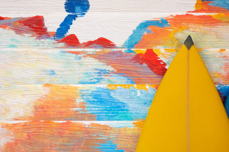 Angle shot of surfboard on wooden wall with many colors (red, blue, orange) as background shows...