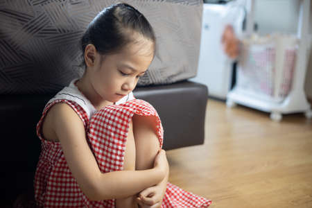 Face close up of cute asian kid girl is sitting on the bedroom floor with sorrow, depressed, upset and scared expression which is due to family punishment and violence, and this is the social problem.の写真素材
