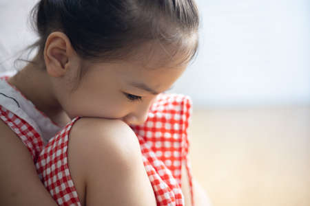 Face close up of cute asian kid girl is sitting on the bedroom floor with sorrow, depressed, upset and scared expression which is due to family punishment and violence, and this is the social problem.の写真素材