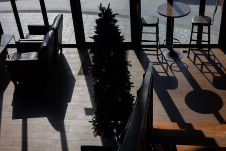 Silhouette and top view from stairway down to office, shop or store with beautiful decorated furniture (desk, table and chairs) and Christmas tree on wooden floor shows retro and vintage urban style.の写真素材