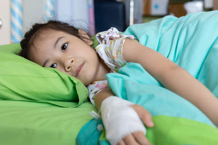 Close up beautiful and adorable face of 5 years old kid asian girl who is sick due to virus infection and receive medication in hospital shows upset and worry for her disease alone on her bed.の写真素材