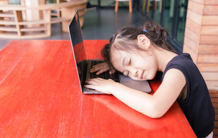 Adorable 5 years old asian girl has finished her studying online through computer laptop outside her...